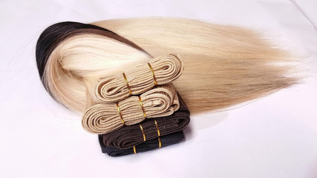 Wefts of long, pale blonde hair laid out on a white surface