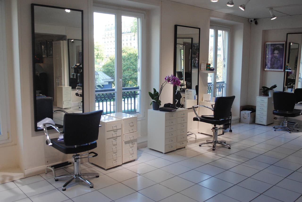 A bright salon floor with black styling chairs and mirrors